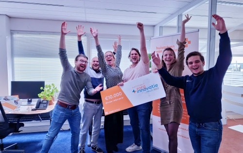 Het team van Huisartsen van Nederland poseert met veel enthousiasme met de winnaarscheque bij hen op kantoor. 